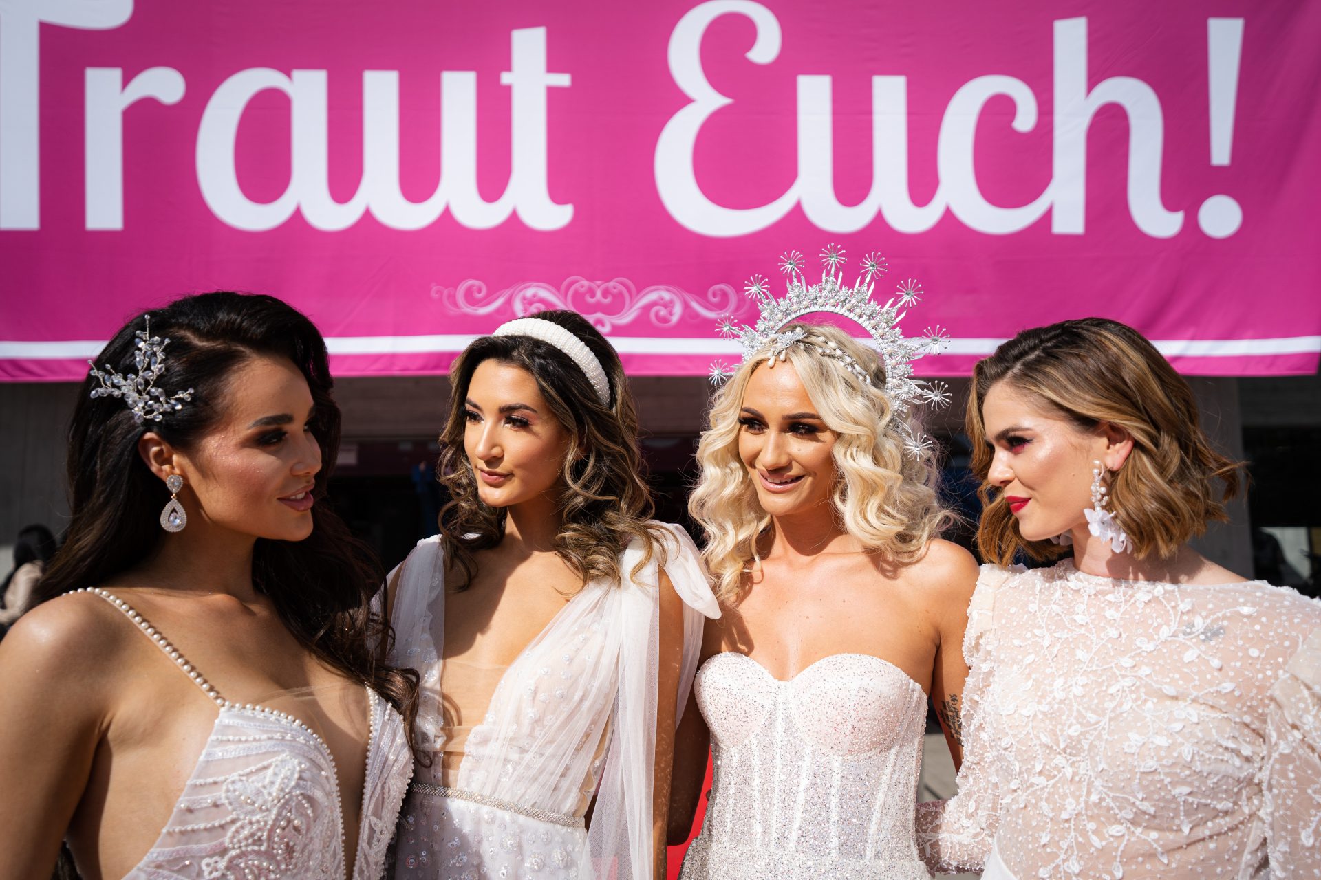 Vier Brautpaare vor Plakat